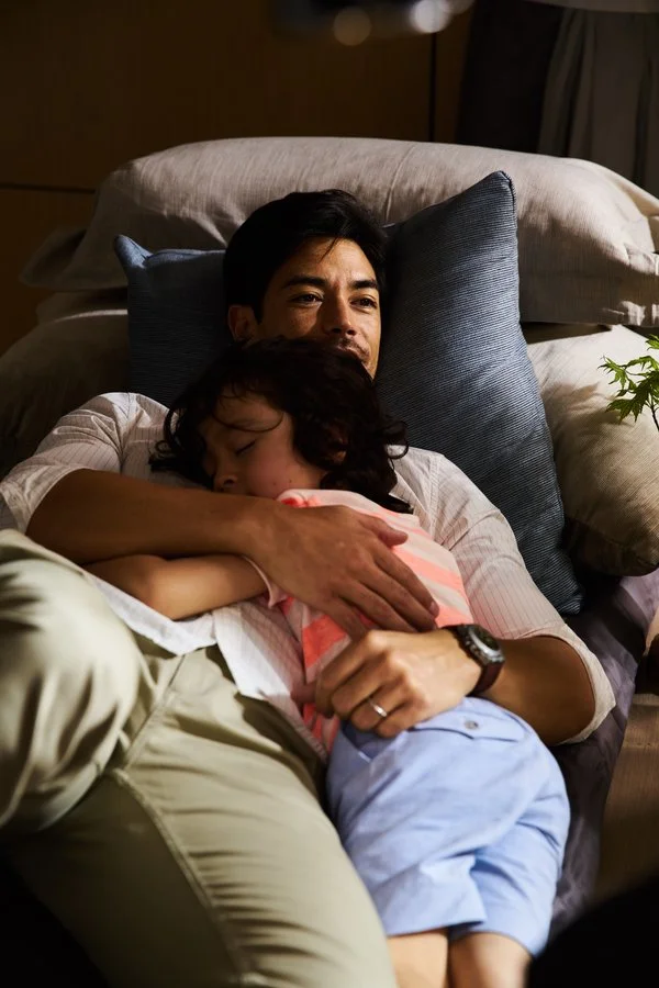Father holding his sleeping daughter on the sofa in warm natural light