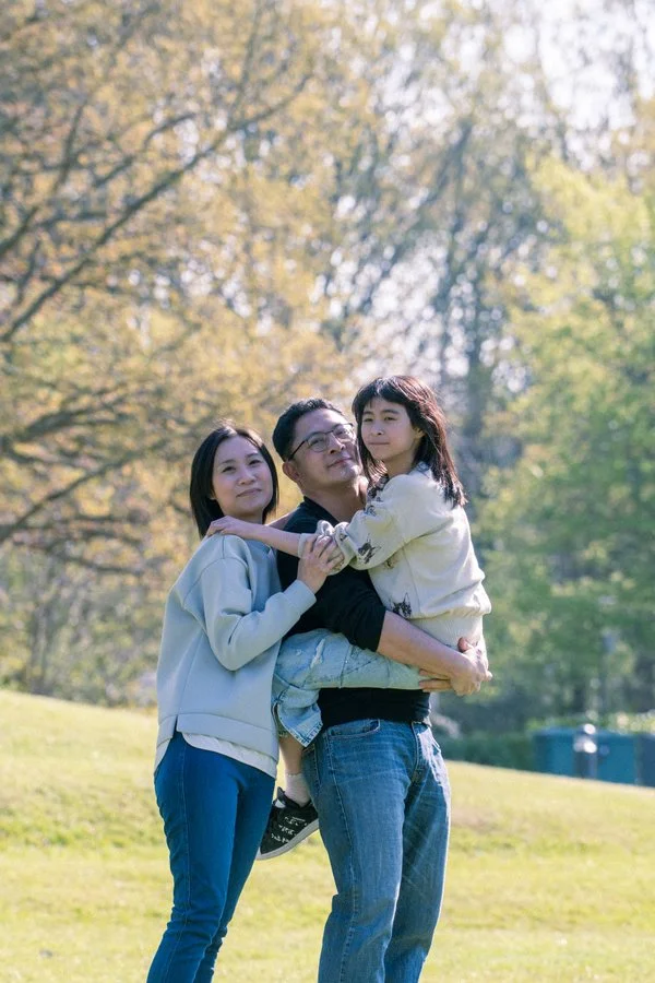 Family portrait in a green park with natural light and relaxed smiles