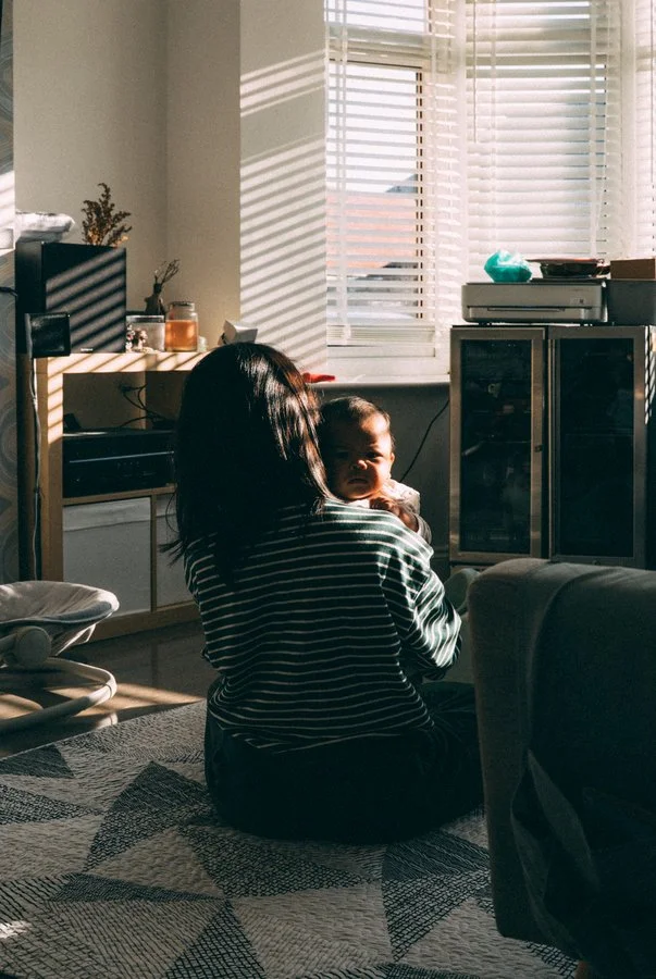 Mother cradling her newborn at home in gentle window light